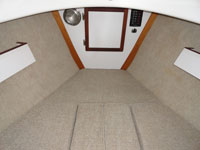 Backrest cushions become fillers to make the entire inside one large berth. There are storage shelves above the backrests.
